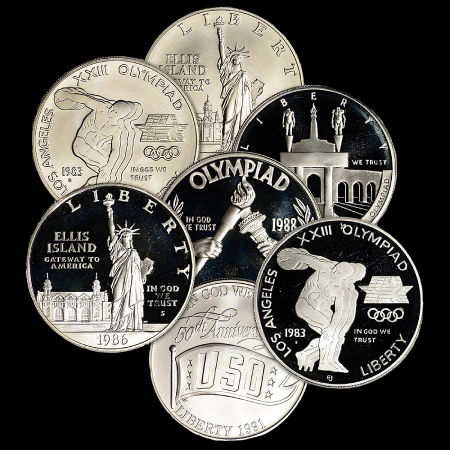 Assorted U.S. $1 silver commemorative coins including 1983 Los Angeles Olympics, 1986 Ellis Island, 1988 Olympiad, and 1991 USO designs in proof and uncirculated finishes